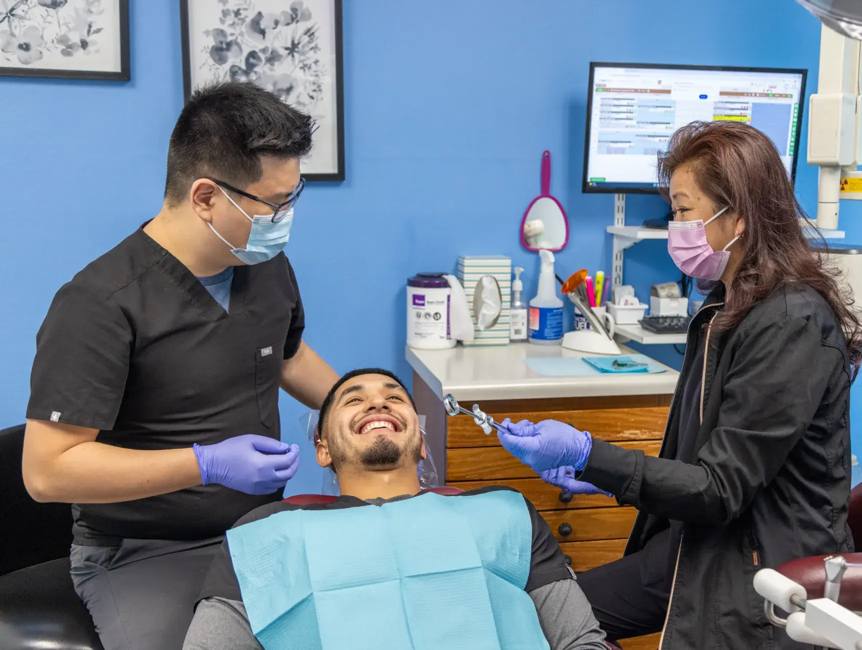 A man sitting in a dentist chair with a woman standing next to him.