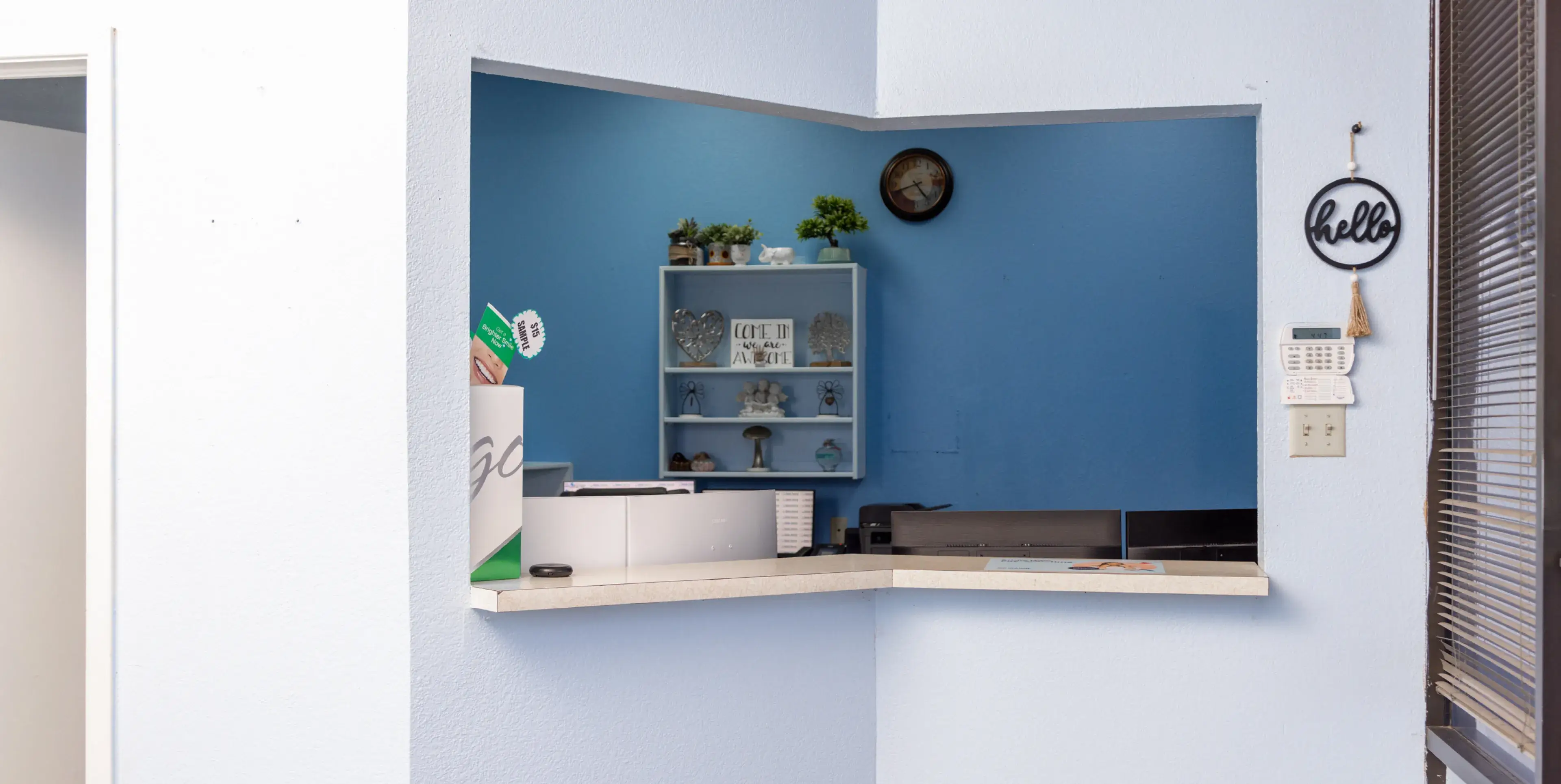 A corner of a room with a shelf and a clock on the wall.