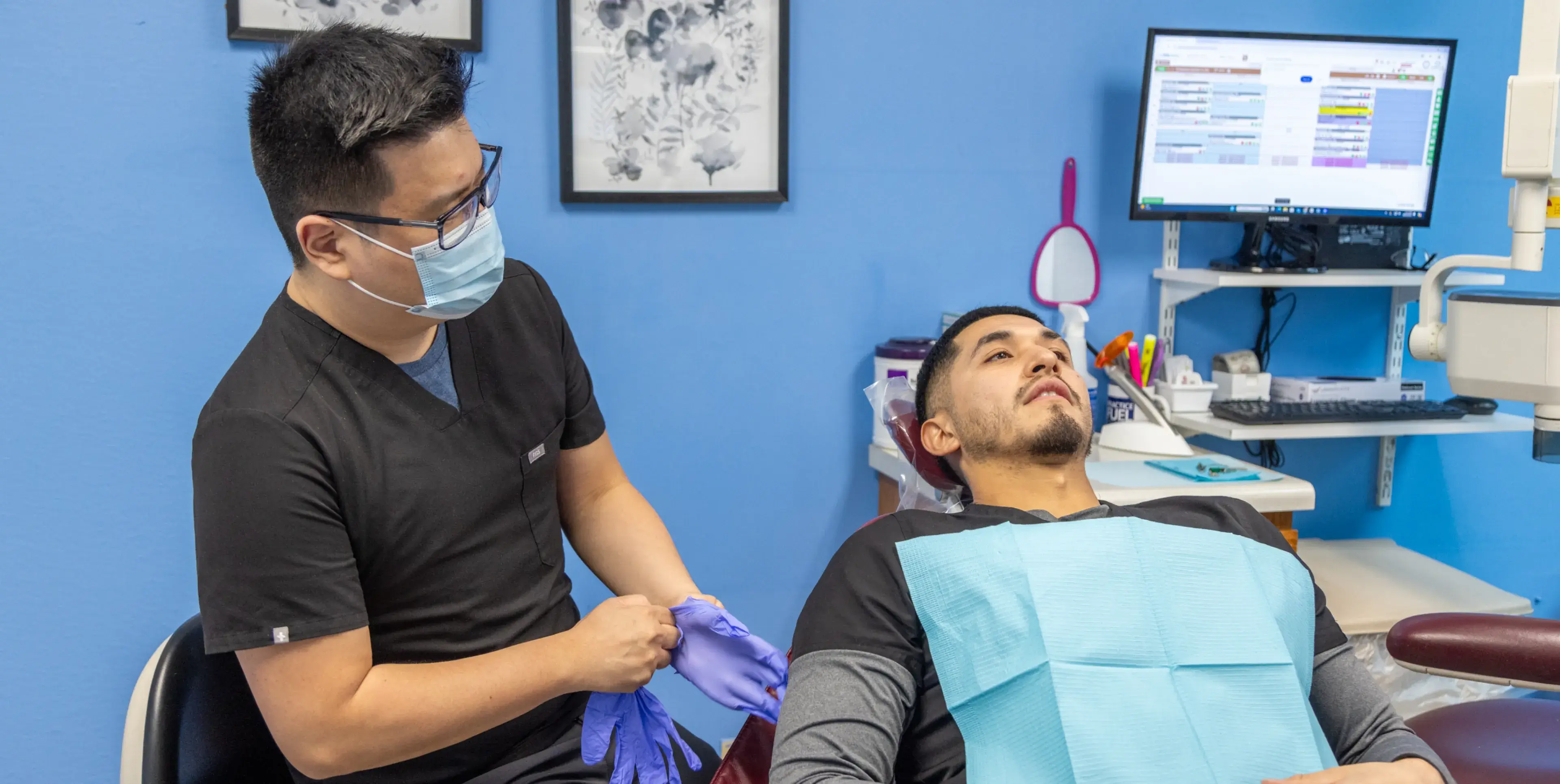 A man in a dentist chair getting his teeth brushed.